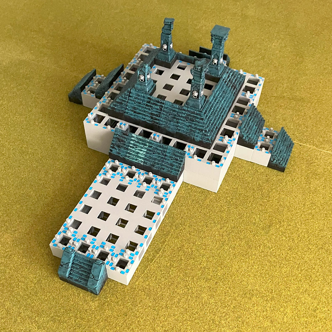 Two freestanding temple structures placed on a classic grass-matted tabletop gaming board – initial setup stage 01