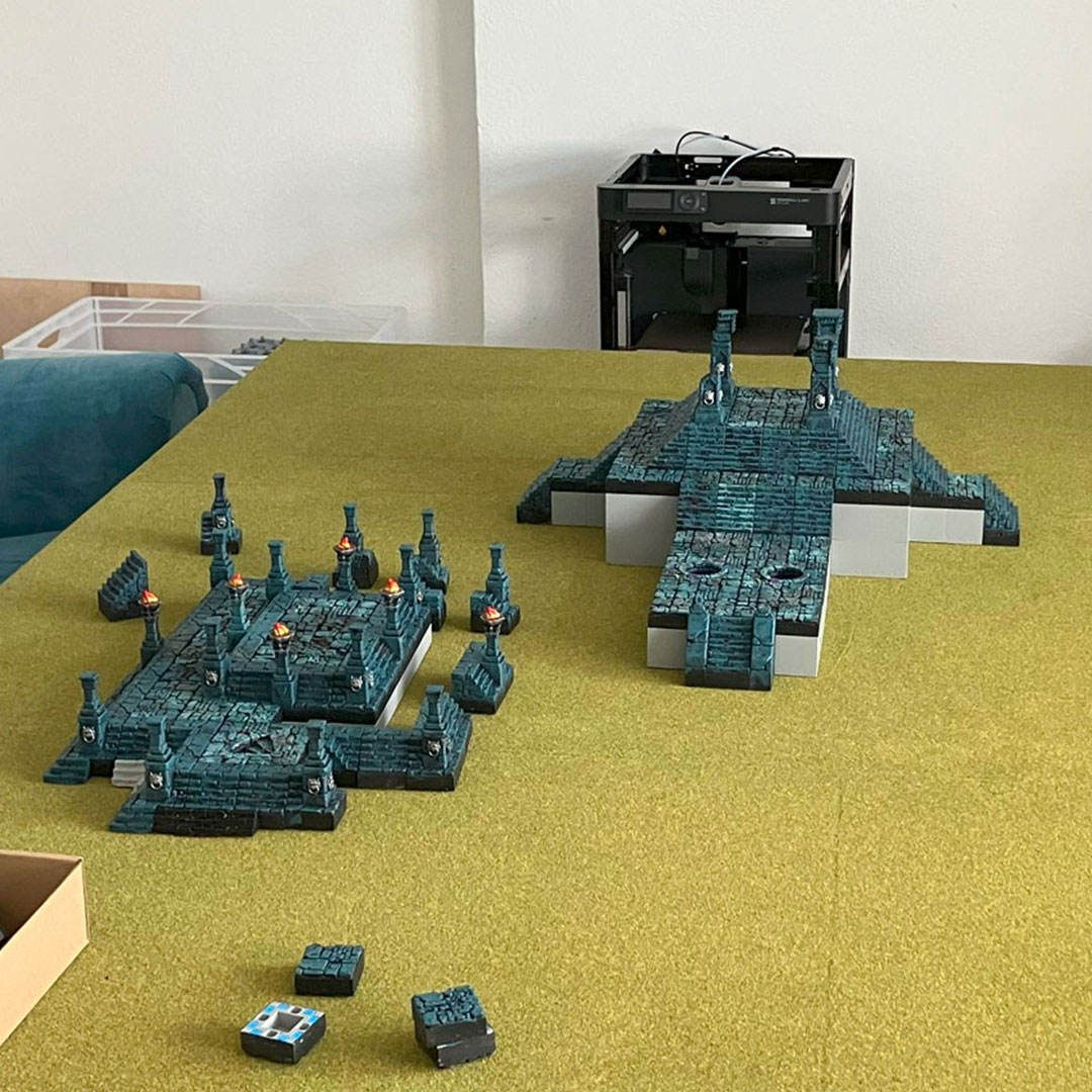 Two freestanding temple structures placed on a classic grass-matted tabletop gaming board – initial setup stage 05